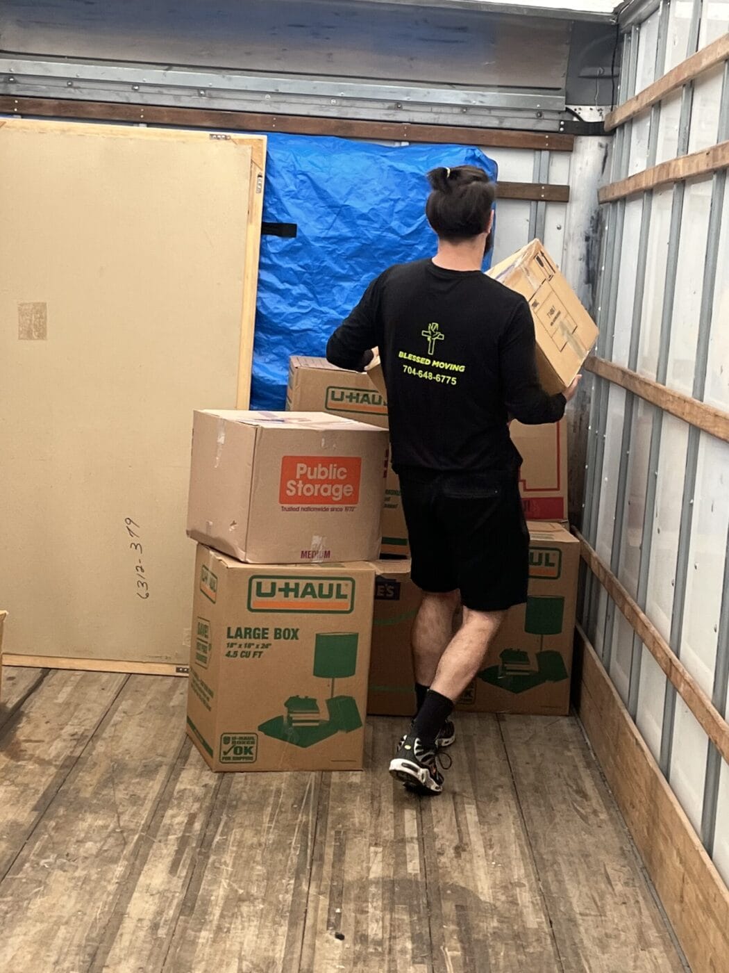 Person organizing boxes inside a moving truck.